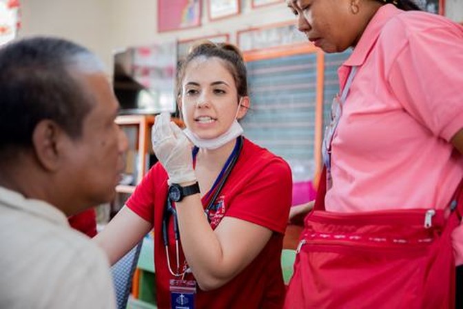 Two ARMS volunteers speak with a patient during a clinic.